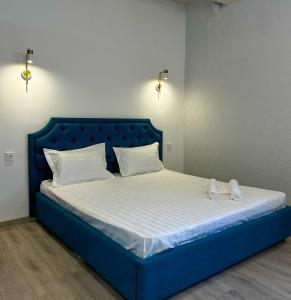 a blue bed with white sheets and white shoes on it at Astina Hotel in Astana