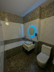 uma casa de banho com um WC e um lavatório com uma luz azul em Astina Hotel em Astana