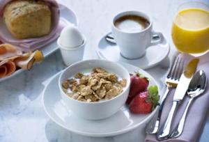 einen Tisch mit einer Schüssel Müsli und einer Tasse Kaffee und Erdbeeren in der Unterkunft BB Snäckan Hönö in Hönö