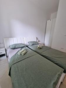 een slaapkamer met een groot bed met groene lakens en kussens bij Bass Apartment in Pula