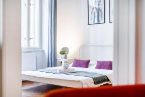 a bedroom with a white bed with purple pillows at GRAND DELUXE ViP APARTMENT in Prague