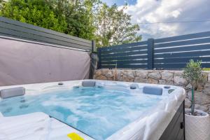 a hot tub in a backyard with a fence at Superior Apartments in Malinska