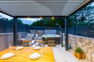 a patio with a table and a hot tub at Superior Apartments in Malinska