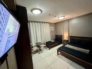 a bedroom with a bed and a flat screen tv at Inn De Avenida, Makati in Manila