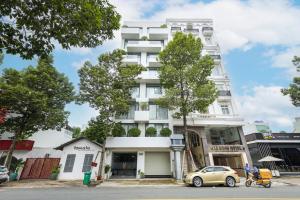 Un bâtiment blanc avec une voiture garée devant. dans l'établissement The Green House - Serviced Apartment, à Thu Dau Mot