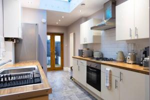 een grote keuken met witte kasten en een wastafel bij Rosa: Seaside home recently renovated in Portsmouth