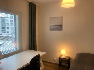 een kamer met een tafel, een lamp en een raam bij Kotimaailma Apartments Seinäjoki - Upea kaksio keskustassa in Seinäjoki