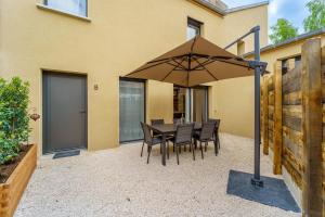 um pátio com uma mesa e cadeiras debaixo de um guarda-sol em Maison calme avec terrasse garage centre-ville B em Dijon