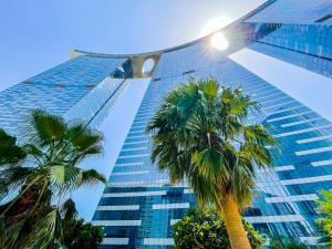 a tall building with palm trees in front of it at Voyage One Bedroom In Reem Island in Abu Dhabi