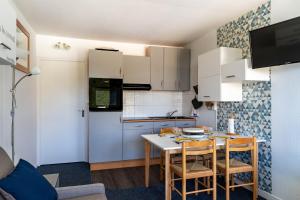 a kitchen with white cabinets and a table and chairs at L'Esperta - Studio proche station de ski et ESF in Eaux-Bonnes