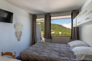 a bedroom with a bed and a large window at L'Esperta - Studio proche station de ski et ESF in Eaux-Bonnes +7 photos