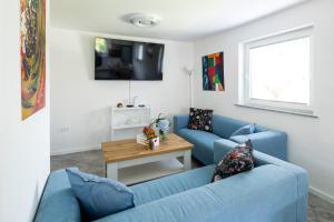 una sala de estar con 2 sofás azules y una mesa. en Aparthouse Jana Breg, en Žirovnica