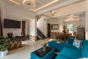 Denver Villa في لونافالا: غرفة معيشة مع أريكة زرقاء وغرفة طعام