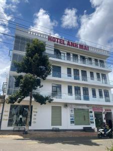 un edificio de apartamentos de hotel con un árbol delante de él en Ánh Mai Hotel, en Bao Loc