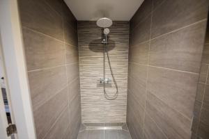 een badkamer met een douche met bruine tegels bij Divine 50m2 Apartment in Tiel
