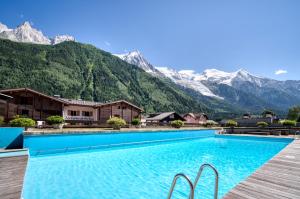 uma piscina de resort com montanhas ao fundo em Appartement Grand Beau Site By C2J em Chamonix-Mont-Blanc