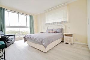 a bedroom with a bed and a chair and a window at Blouberg heights in Cape Town