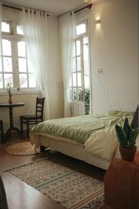 a bedroom with a bed and a table and windows at Art Garden Dalat in Da Lat