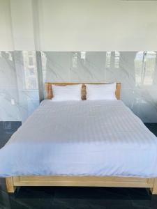 1 cama grande con sábanas y almohadas blancas en Ánh Mai Hotel, en Bao Loc