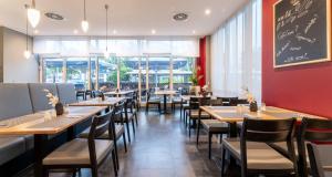 a dining room with tables and chairs and a chalkboard at PLAZA Premium Köln in Cologne