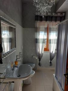 ein Badezimmer mit einem Waschbecken, einem WC und einem Kronleuchter in der Unterkunft La Reggia del Corso in Vieste