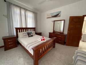 a bedroom with a bed with a dresser and a mirror at Didi's Dream apartments in Anse Kerlan