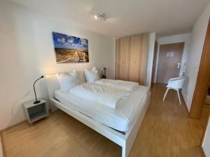 a bedroom with a white bed with a desk and a chair at Bremen Weser Best View Apartment in Bremen