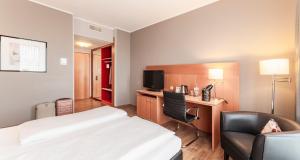 Habitación de hotel con cama y silla en PLAZA Premium Köln en Colonia