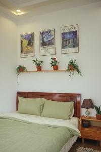 a bedroom with a bed and three pictures on the wall at Art Garden Dalat in Da Lat