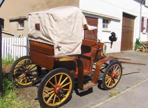 an old horse drawn carriage parked in a driveway at La Cabane du Trappeur V d N in Voellerdingen