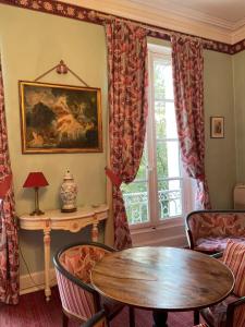 Hôtel Château des Jacobins في آجا: غرفة معيشة مع طاولة وكراسي ونافذة