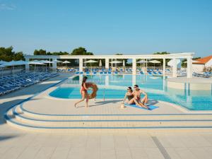 een groep mensen die rond een zwembad zitten bij Bluesun Hotel Alga in Tučepi