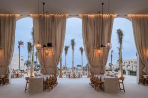 um salão de banquetes com mesas, cadeiras e palmeiras em Serry Beach Resort em Hurghada