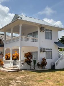 Casa blanca con un gran porche delantero en Didi's Dream apartments, en Anse Kerlan
