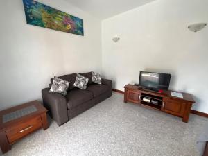sala de estar con sofá y TV en Didi's Dream apartments, en Anse Kerlan