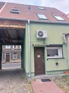 ein grünes Gebäude mit einer Tür und einer Klimaanlage in der Unterkunft Apartament Krawcownia in Świebodzin