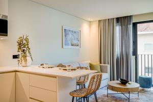 波尔图Blissful Suites Porto by gaiarooms的配有桌椅的厨房和客厅