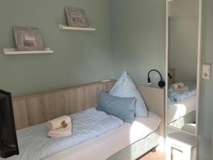 Zimmer mit einem Bett, Handtüchern und einem Spiegel in der Unterkunft Hotel Garni Goldener Anker in Greetsiel