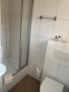 een badkamer met een douche, een toilet en een wastafel bij Hotel Garni Goldener Anker in Greetsiel