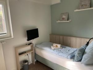 a small bedroom with a bed with a teddy bear on it at Hotel Garni Goldener Anker in Greetsiel