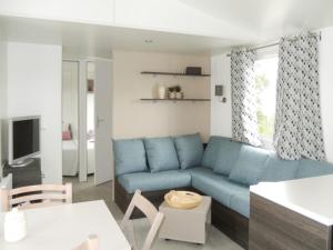 - un salon avec un canapé bleu et une table dans l'établissement BUNGALOW LUXE MAZET ROYAL carabasse Vias plage ACCES proximité PISCINE, à Vias