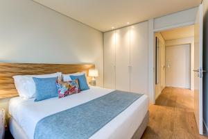 a bedroom with a large white bed with blue pillows at Blissful Suites Porto in Porto