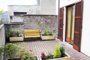 a wooden bench sitting on a patio with plants at Alexander Rooms in Tirano