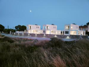 根納迪的住宿－Alpha Villas，一排白色房子,上面有灯光,在草地上