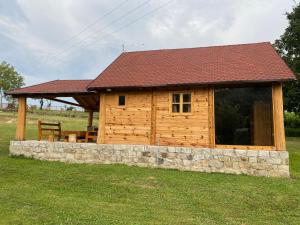 a log cabin with a roof and a stone wall at Vikendica Milošević in Arandelovac