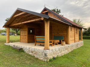 una cabaña de madera con un banco en el césped en Vikendica Milošević en Arandjelovac