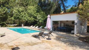 een zwembad met stoelen en een parasol en een huis bij La Bastide Blanche Magnifique villa 5 étoiles 5 chambres et piscine privée sur 6500 m VAR in Lorgues