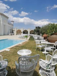 un gruppo di sedie e tavoli bianchi accanto a una piscina di B&B Le Torri a Santeramo in Colle