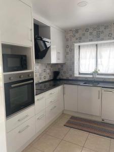 a kitchen with white cabinets and a sink and a window at Casa do coral in Peniche
