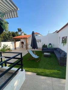 a backyard with a couch and an umbrella and grass at Casa do coral in Peniche